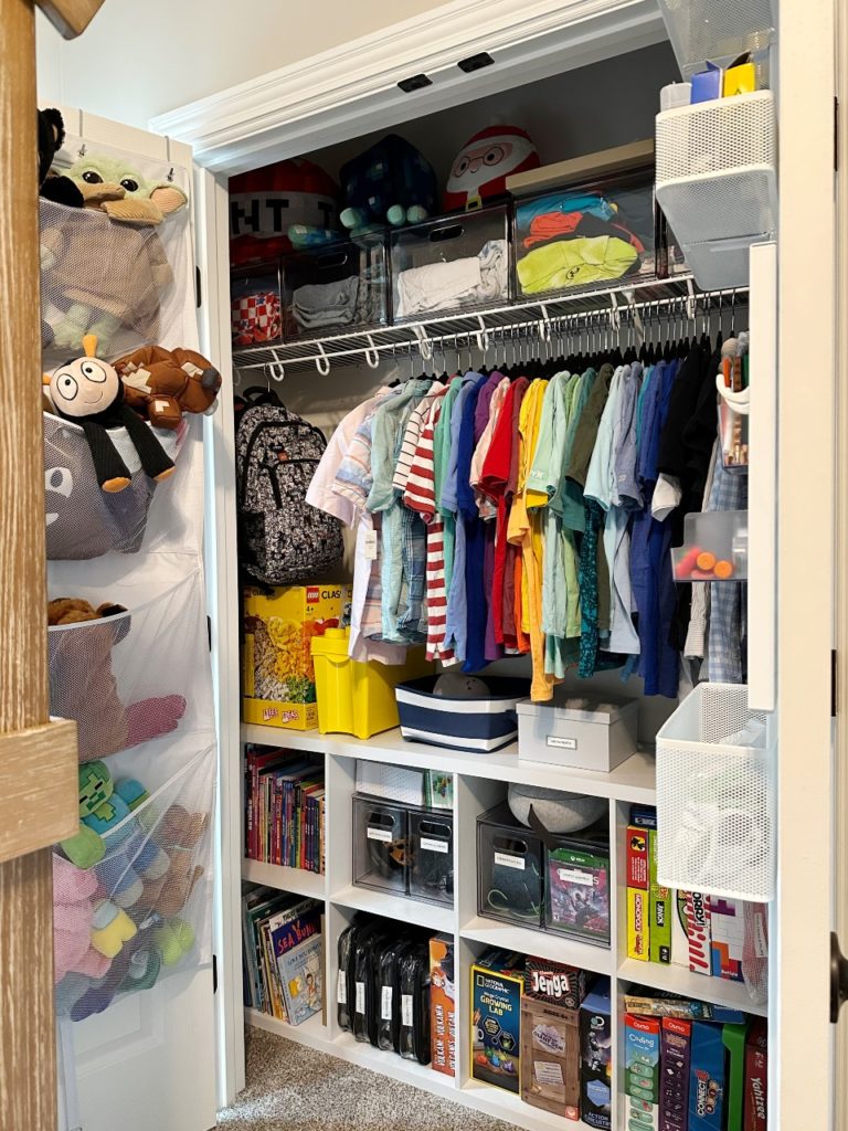 an organized closet with cube storage for games, Legos, and toys, a mesh over the door organizer for stuffed animals, and a metal over the door organizer for arts and crafts supplies